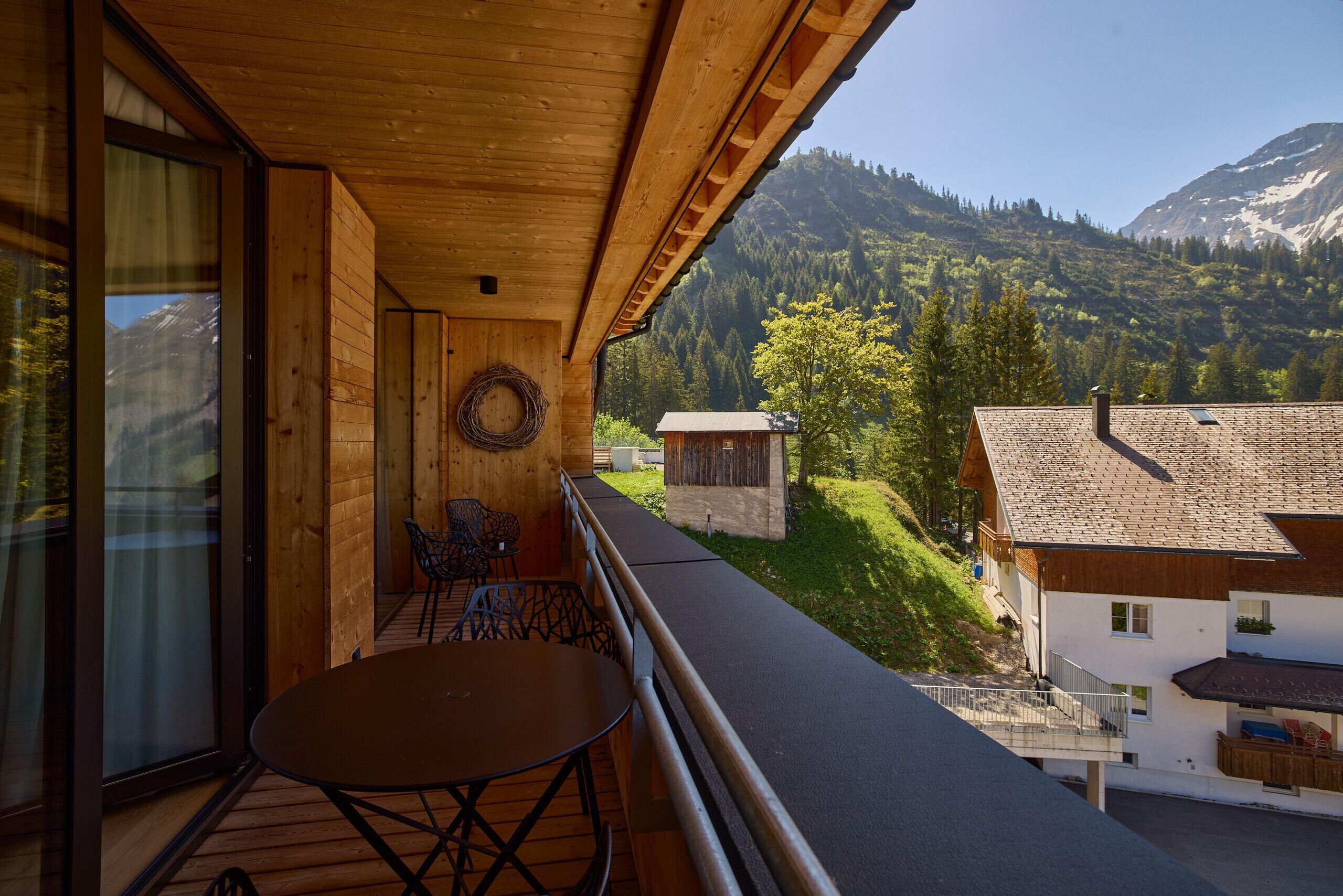 A balcony with a table and chairs, overlooking a mountainous landscape.