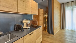 A modern kitchen with wooden cabinets, a built-in espresso machine, and a sleek countertop. - 8005 Alpin Retreat Grand 5 (Schröcken)