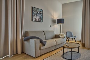 Ein modernes Wohnzimmer mit einer Couch, einem Sessel, einem kleinen runden Tisch und einer Lampe.