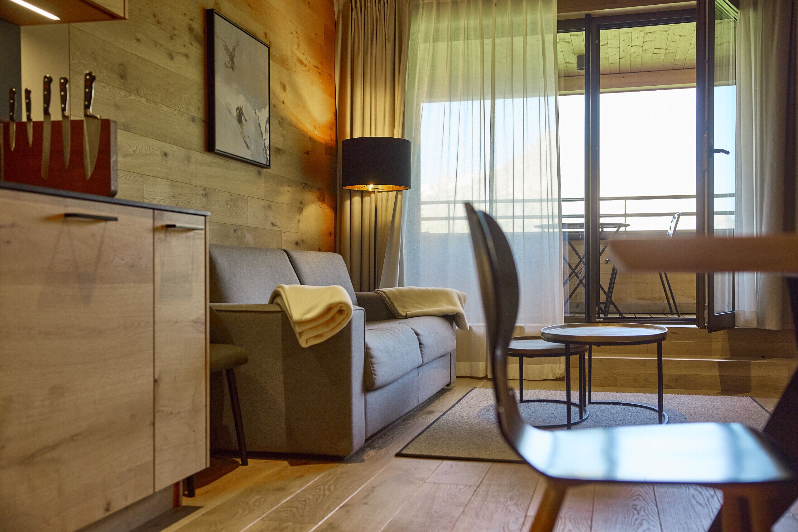 Ein modernes Wohnzimmer mit einer Couch, einem Sessel, einem kleinen Tisch und einem Schrank.