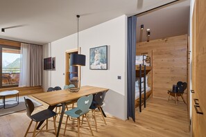 A modern room with a wooden dining table, chairs, a TV, and a bunk bed. - 8007 Alpine Retreat 7 (Schröcken)