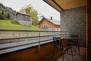 Ein Balkon mit Bergblick, ein Holzgebäude und eine Steinmauer.