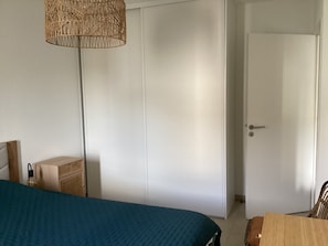 A bedroom with a bed, a wardrobe, a door, and a hanging lamp. - Air-conditioned one-bedroom apartment near the beach with parking and a pool (Le Lavandou)