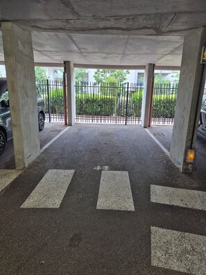 Ein Parkplatz mit Betonpfeilern, einem Metallgitter und einer Fußgängerüberweg.