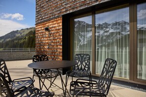 A terrace with a table and chairs, overlooking a mountainous landscape. - 8009 Arlberg Grand Residence 9 (Schröcken)