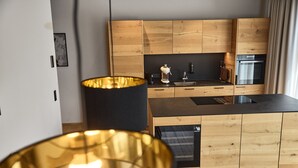 A modern kitchen with wooden cabinets, a black countertop, and a built-in oven. - 8009 Arlberg Grand Residence 9 (Schröcken)