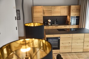 Eine moderne Küche mit Holzschränken, einer schwarzen Arbeitsplatte und einem eingebauten Ofen.