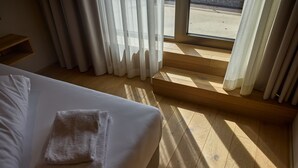 A hotel room with a bed, a wooden floor, and a view through a window. - 8009 Arlberg Grand Residence 9 (Schröcken)
