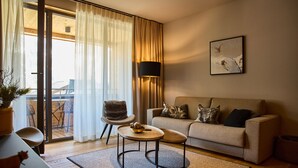 Een moderne woonkamer met een bank, een klein rond tafeltje, een fauteuil en een vloerlamp.