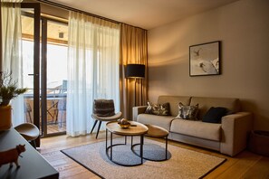 Ein modernes Wohnzimmer mit einer Couch, einem kleinen runden Tisch, einem Sessel und einer Stehlampe.