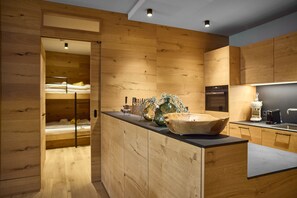 A modern kitchen with wooden cabinetry and a central island. - 8010 Alpine Residence 10 (Schröcken)