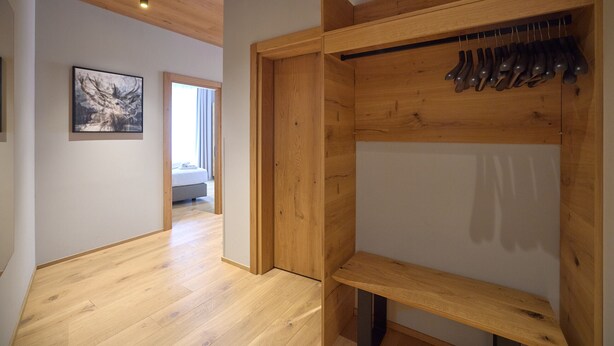 A room with wooden flooring, a wooden wardrobe with a shoe rack, and a framed picture on the wall. - 8012 Alpin Retreat Grand 12 (Schröcken)