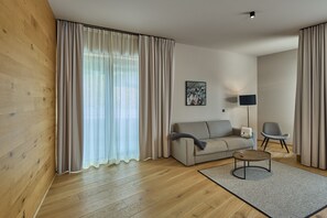 A modern living room with a sofa, a coffee table, and a lamp. - 8012 Alpin Retreat Grand 12 (Schröcken)
