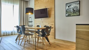 A modern dining area with a wooden table and chairs, a pendant light, and a framed picture on the wall. - 8012 Alpin Retreat Grand 12 (Schröcken)