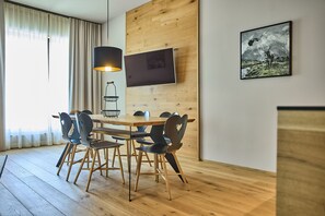 A modern dining area with a wooden table and chairs, a pendant light, and a framed picture on the wall. - 8012 Alpin Retreat Grand 12 (Schröcken)