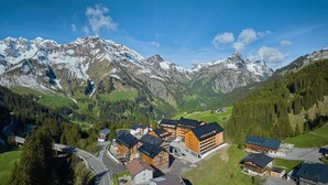 A mountain resort with chalet-style buildings, a ski lift, and snow-capped peaks in the background. - 8012 Alpin Retreat Grand 12 (Schröcken)