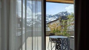 A room with a view of snow-capped mountains, a table with chairs, and a building with a sloped roof. - 8012 Alpin Retreat Grand 12 (Schröcken)