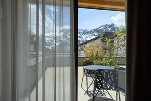 A room with a view of snow-capped mountains, a table with chairs, and a building with a sloped roof. - 8012 Alpin Retreat Grand 12 (Schröcken)
