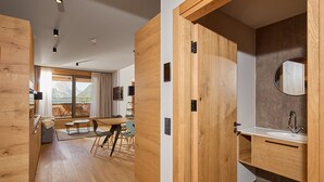 Ein modernes Interieur mit Holzböden, einem Essbereich mit Tisch und Stühlen sowie einem Badezimmer mit Waschbecken und Spiegel.