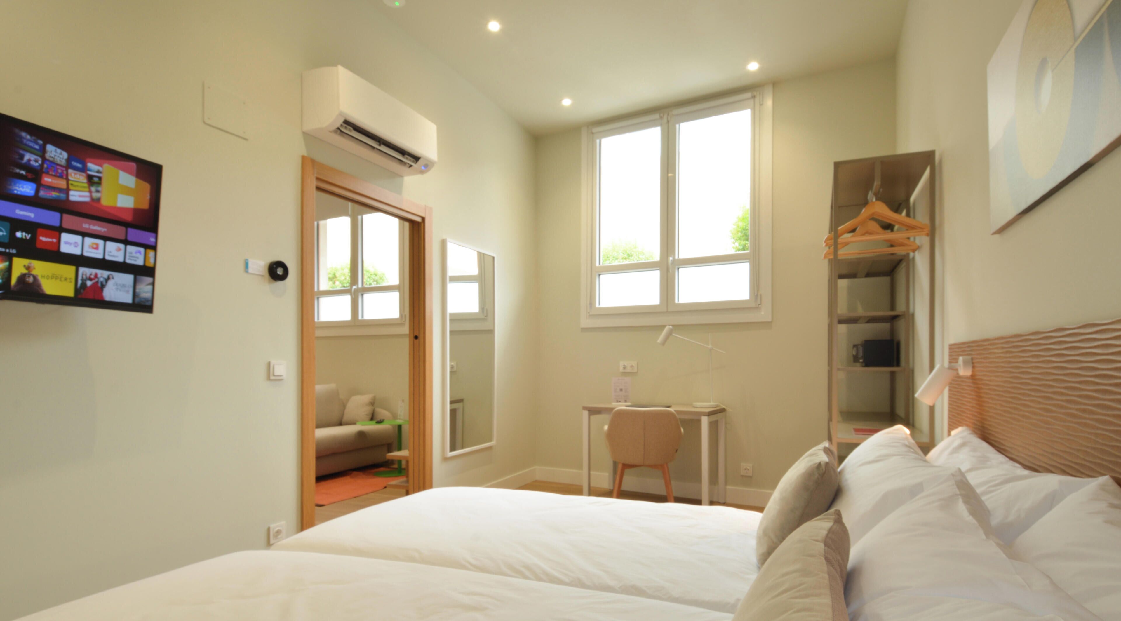 Een slaapkamer met een bed, een bureau, een stoel, een kledingkast en een airconditioning.