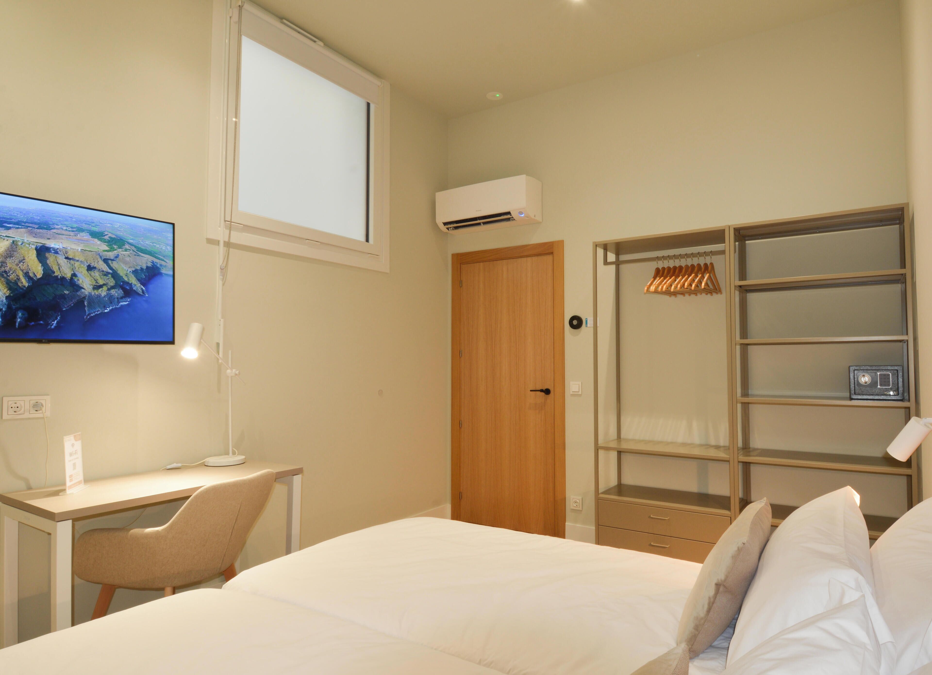 Une chambre d’hôtel équipée d’un lit, d’un bureau, d’une chaise, d’une télévision, d’un climatiseur et d’une armoire.