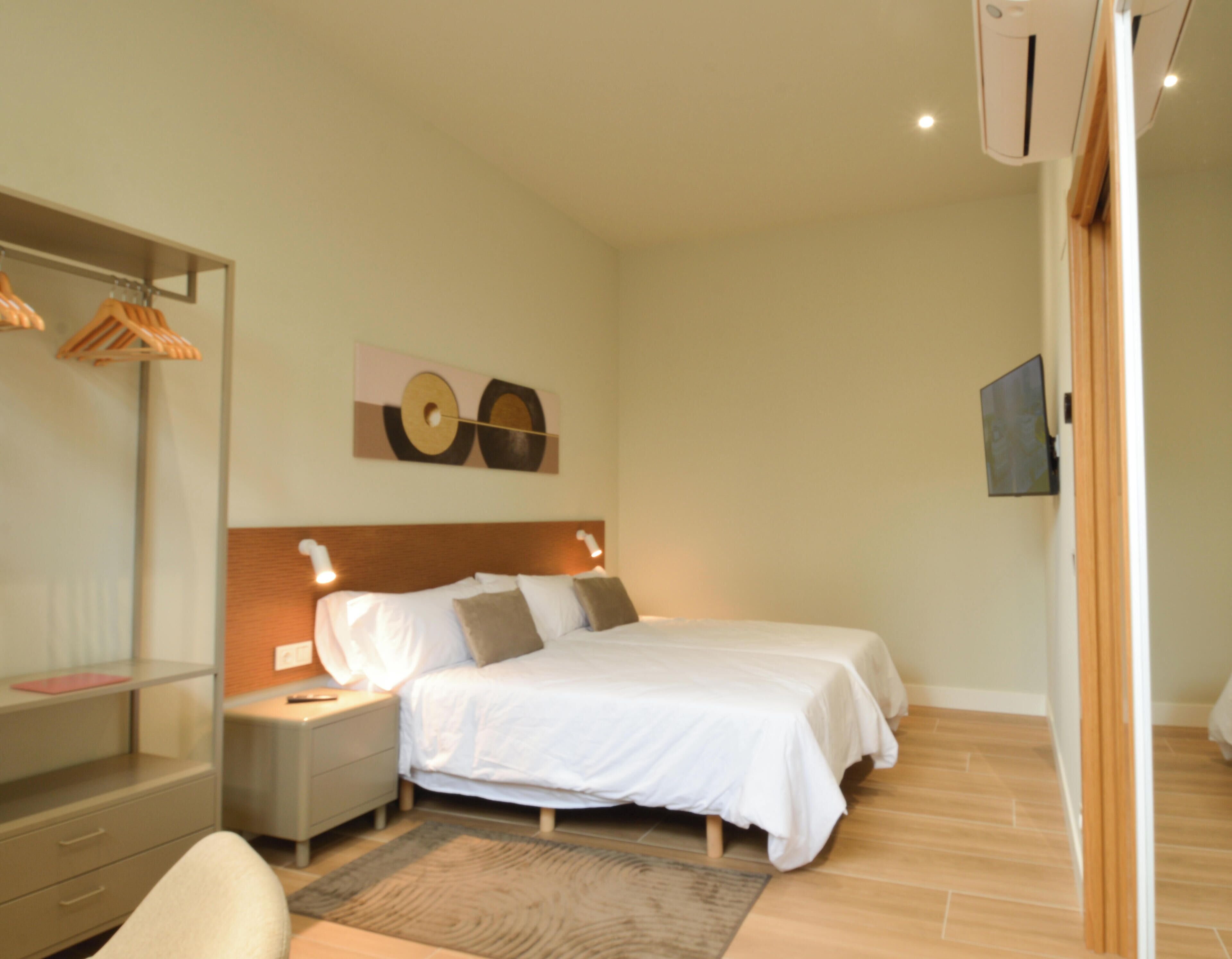 A hotel room with a bed, bedside tables, a wardrobe, and a wall-mounted artwork.
