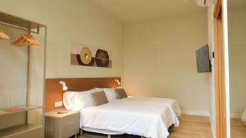 A hotel room with a bed, bedside tables, a wardrobe, and a wall-mounted artwork.