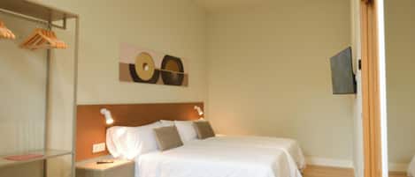A hotel room with a bed, bedside tables, a wardrobe, and a wall-mounted artwork.
