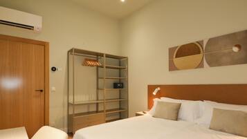 Een hotelkamer met een bed, een kledingkast, een nachtkastje en een kunstwerk aan de muur.