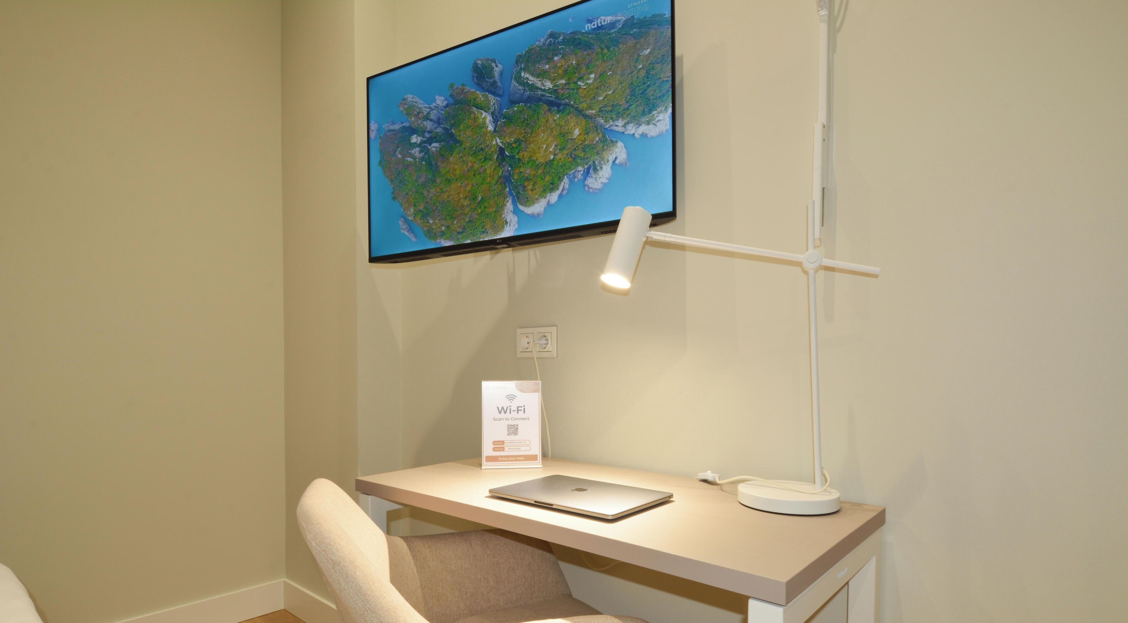 A workspace with a desk, a laptop, a monitor, and a desk lamp.