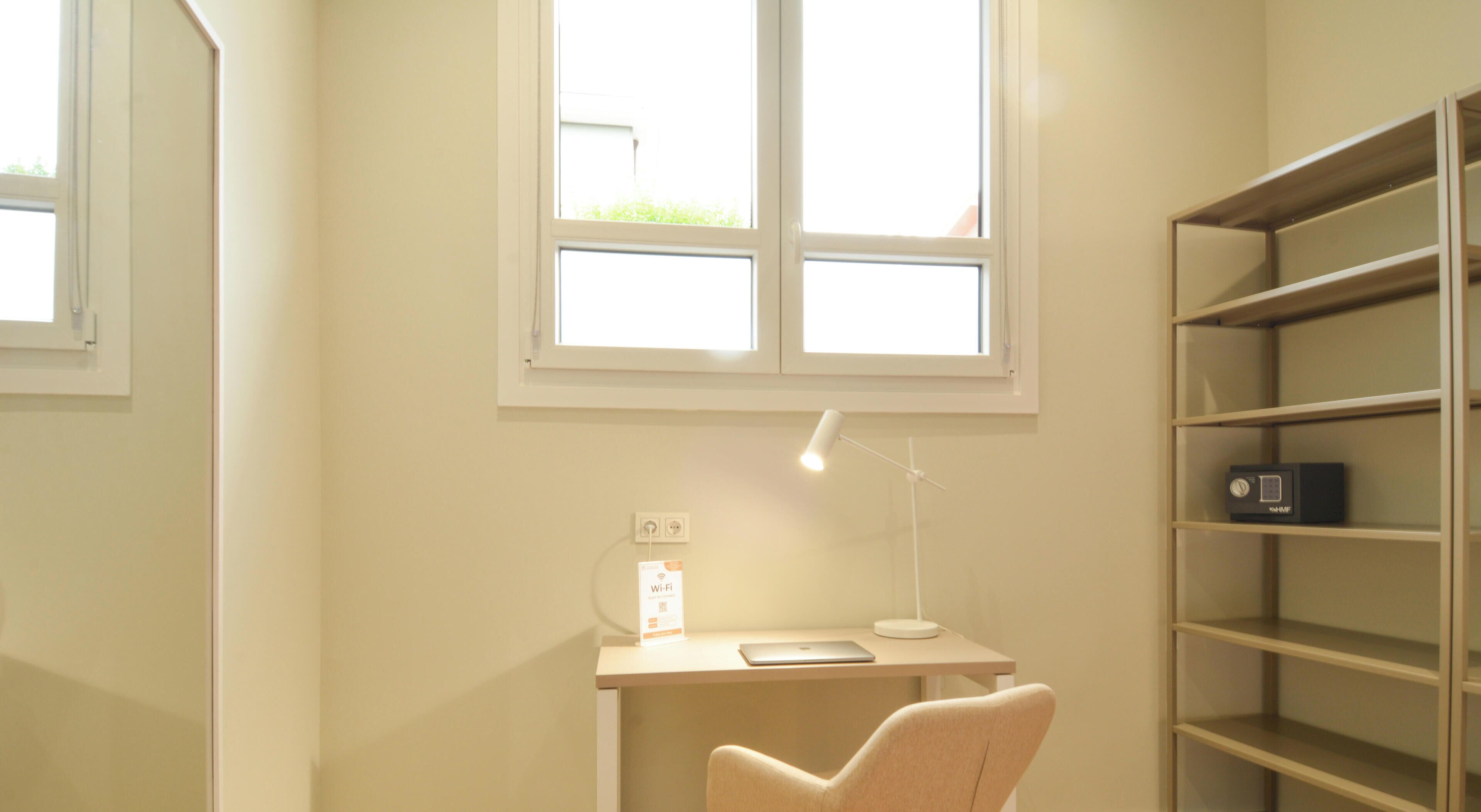A room with a desk, chair, shelves, and a window.