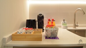 A kitchen counter with a coffee maker, a basket of snacks, and a bottle of orange juice.