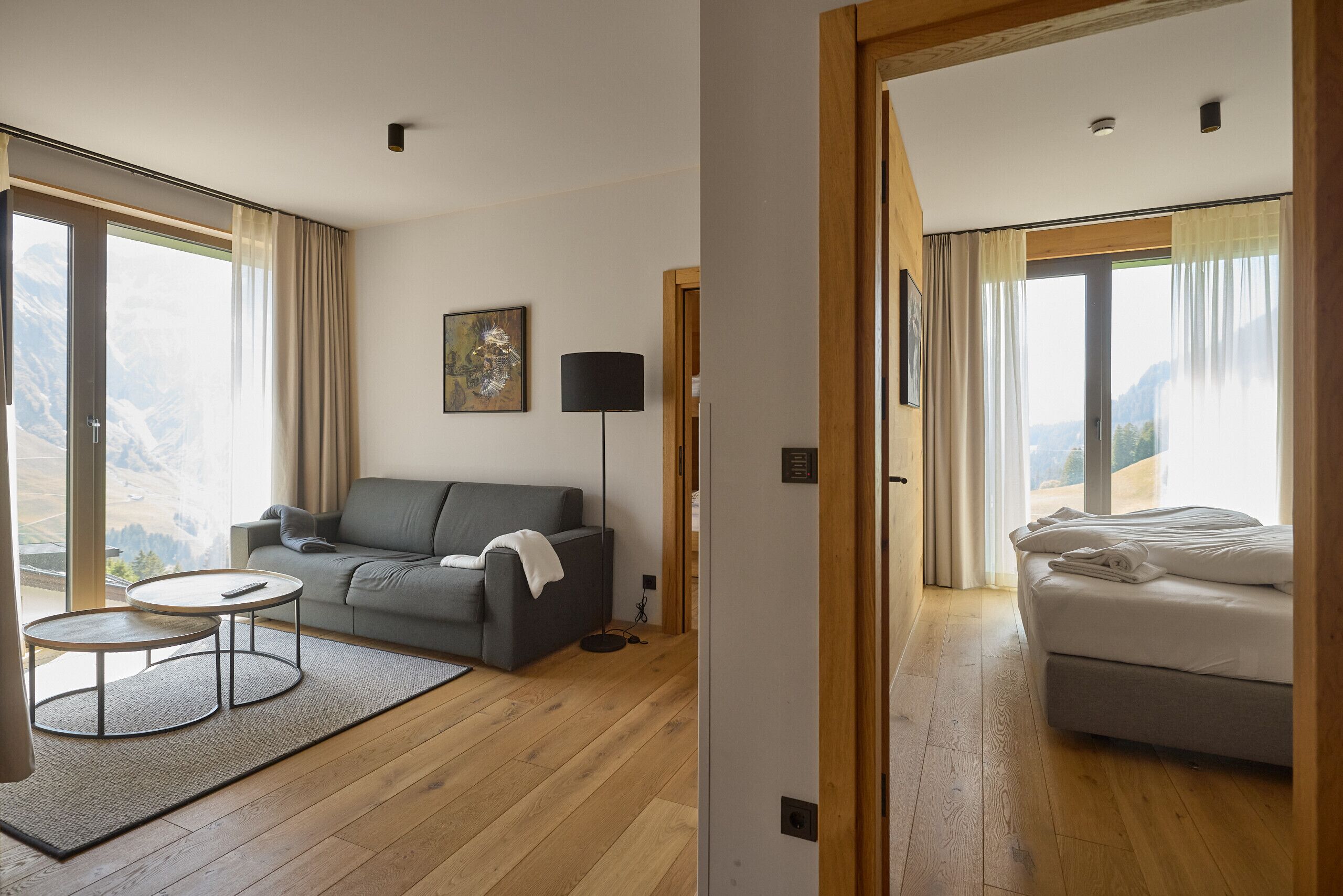 Ein modernes Hotelzimmer mit einer Couch, einem kleinen runden Tisch, einer Lampe und einem Bett.