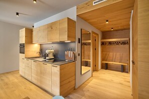 A modern kitchen with wooden cabinetry and a built-in island. - 8018 Summit Residence 18 (Schröcken)