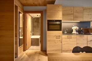 A modern kitchen with wooden cabinetry, a built-in oven, and a coffee machine. - 8019 Sky Residence 19 (Schröcken)