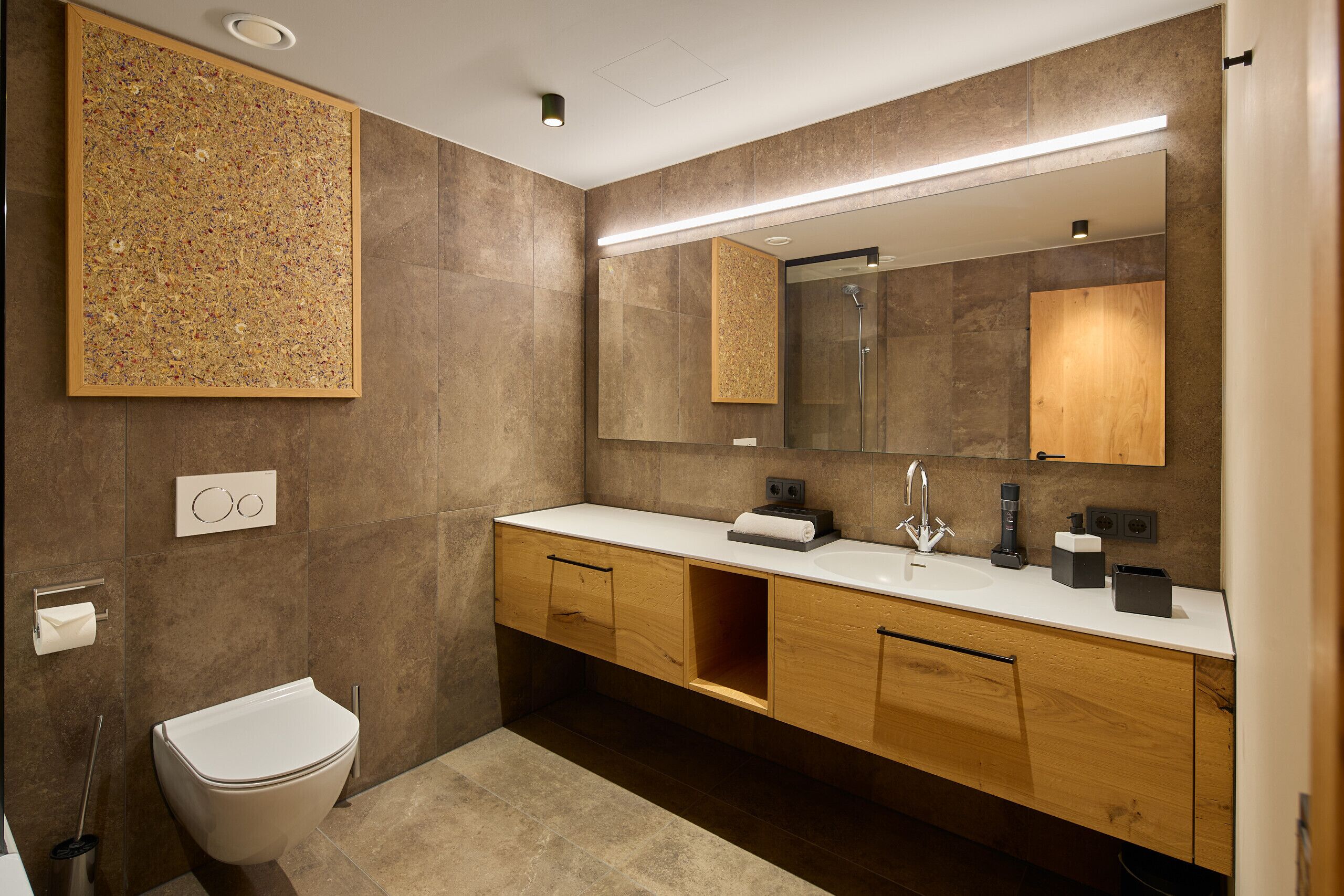 Une salle de bain moderne avec un grand miroir, des toilettes et un lavabo doté d’un meuble-vasque en bois.
