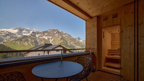 A wooden balcony with a table and chairs, overlooking a mountain landscape. - 8020 Alpine Residence 20 (Schröcken)