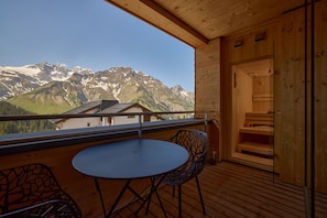 A wooden balcony with a table and chairs, overlooking a mountain landscape. - 8020 Alpine Residence 20 (Schröcken)