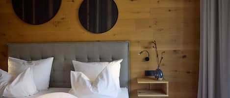 A bedroom with a bed, pillows, a bedside table with a lamp, and wall decorations.