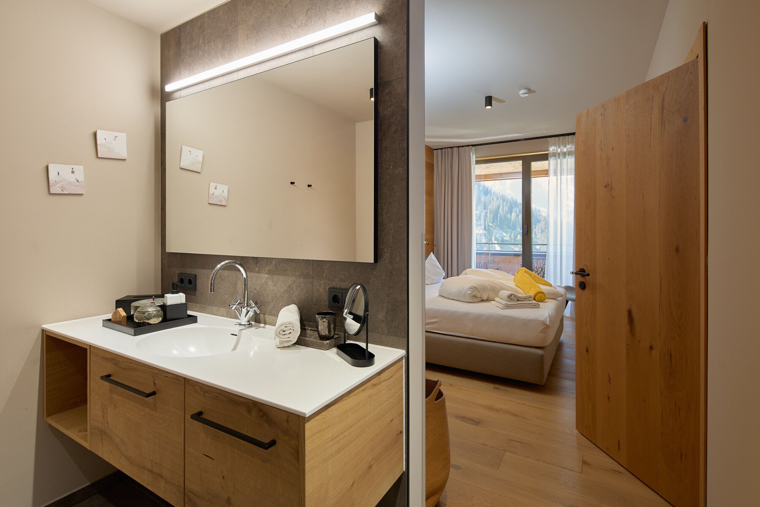 A modern bathroom with a large mirror, wooden cabinets, and a sink.