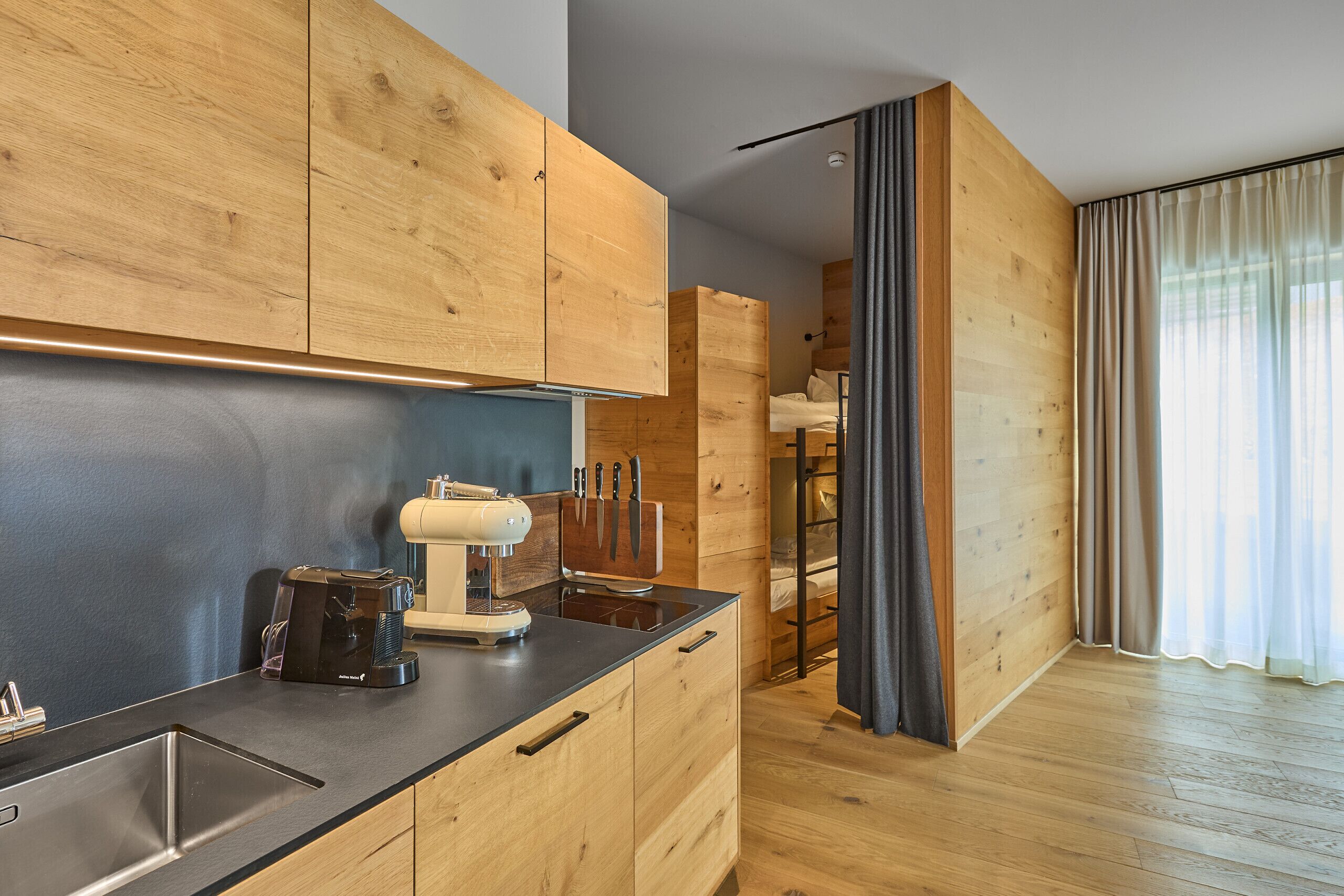 Eine moderne Küche mit Holzschränken, einer integrierten Espressomaschine und einer eleganten Arbeitsplatte.