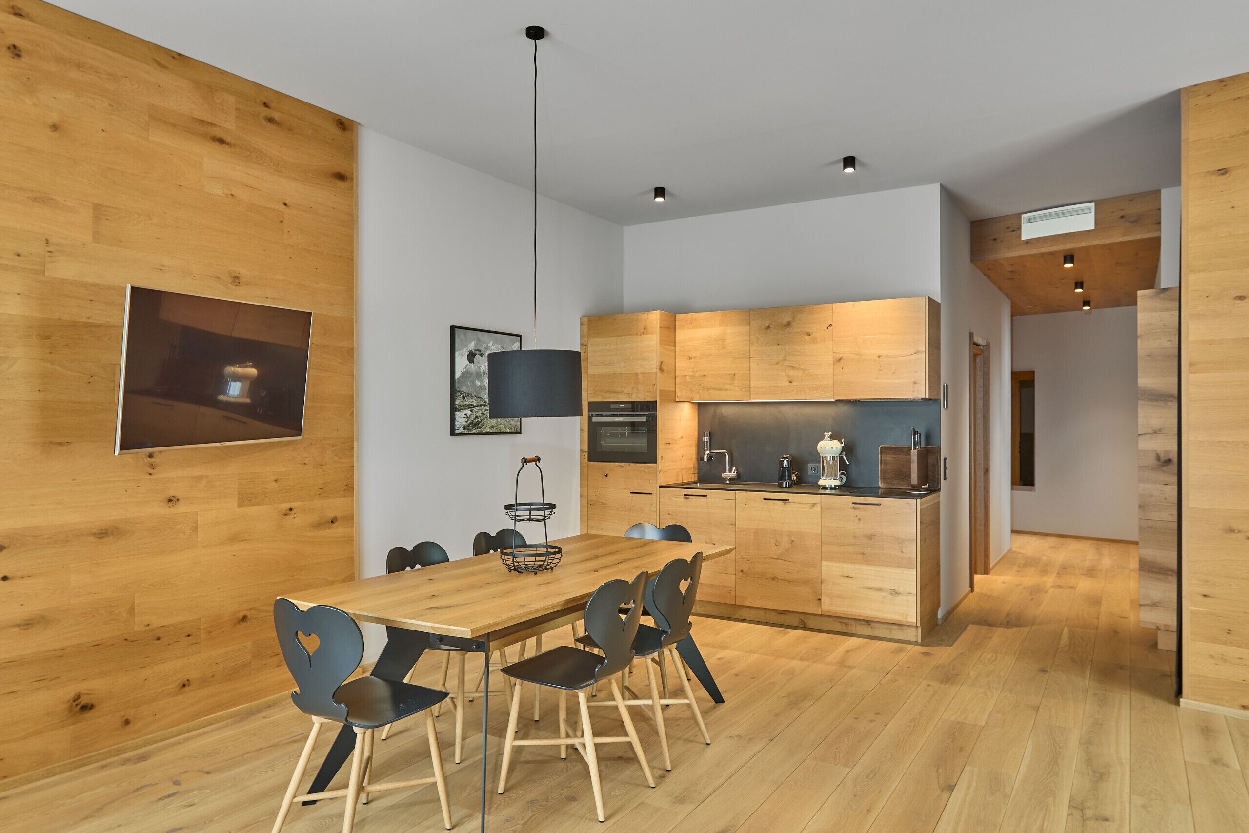 A modern kitchen with wooden cabinets, a dining area with a wooden table and chairs, and a small kitchen island.