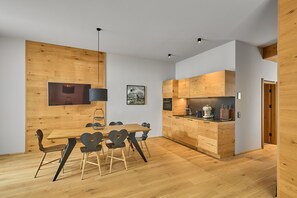 A modern kitchen with wooden cabinetry and a dining area with a wooden table and chairs. - 8021 Alpin Retreat Grand 21 (Schröcken)