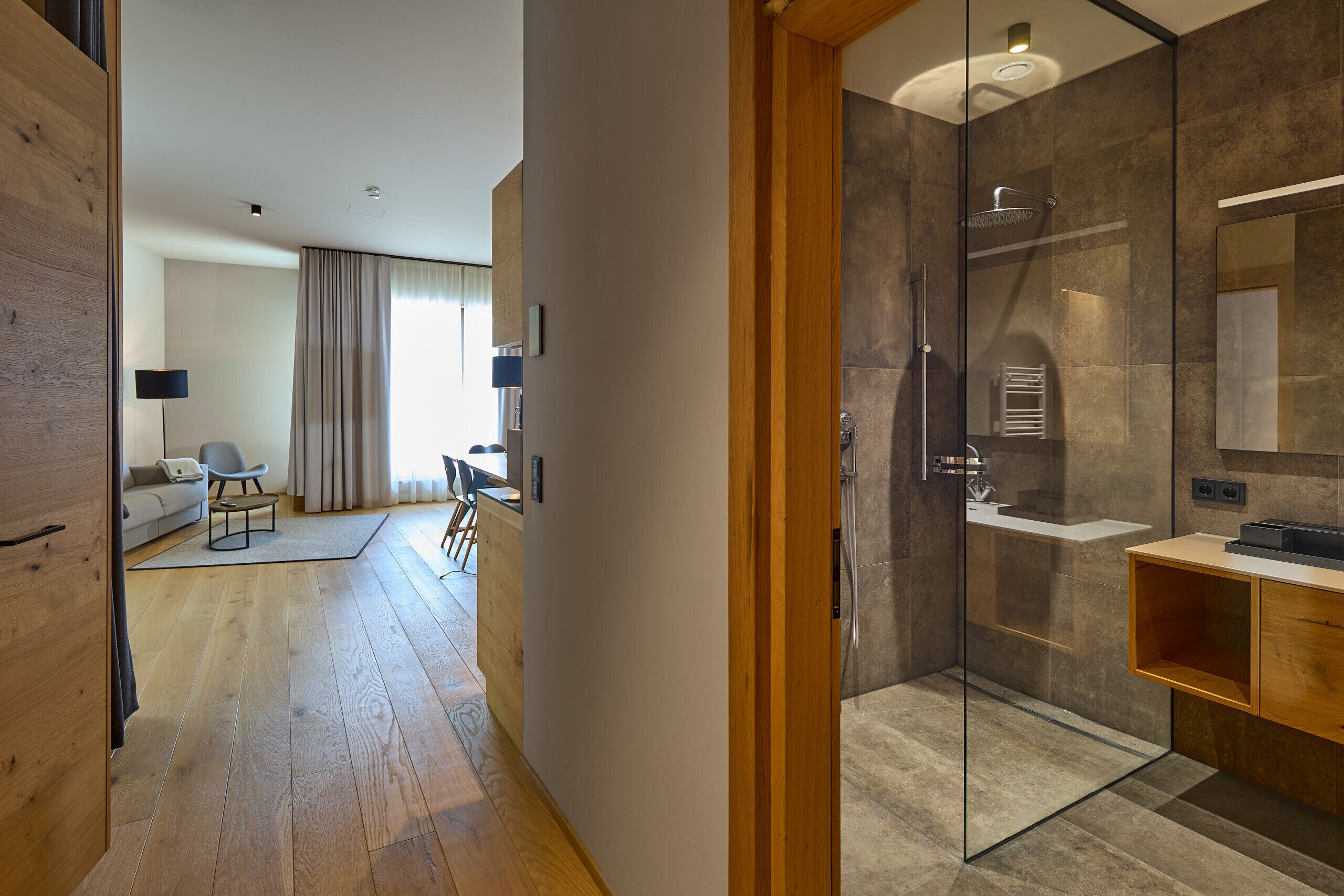 A modern bathroom with a glass shower enclosure, a wooden vanity, and a large mirror.