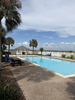 A swimming pool with a gazebo, palm trees, and a white fence. - Sausalito Beach Retreat | Pool | Beach | Relax (Galveston)