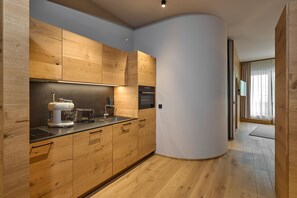 A modern kitchen with wooden cabinets, a built-in oven, and a coffee machine. - 8023 Alpin Retreat Grand 23 (Schröcken)