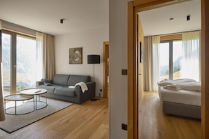 Una habitación de hotel moderna con sofá, una mesita redonda, una lámpara y una cama.