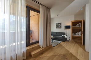 Una sala de estar moderna con un sofá, una mesita de centro y una lámpara. Se ve una escalera que lleva a un espacio al aire libre.