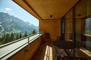 A wooden balcony with a table and chairs, overlooking a mountainous landscape. - 8027 Summit Residence 27 (Schröcken)