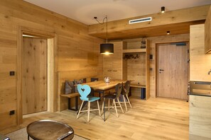 A wooden interior with a dining area, bench seating, and a kitchen with wooden cabinets. - 8028 Sky Residence 28 (Schröcken)